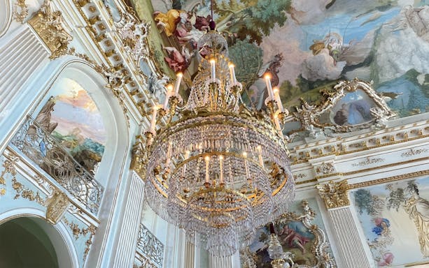 Ornate chandelier and frescoed ceiling in Nymphenburg Palace, Munich.