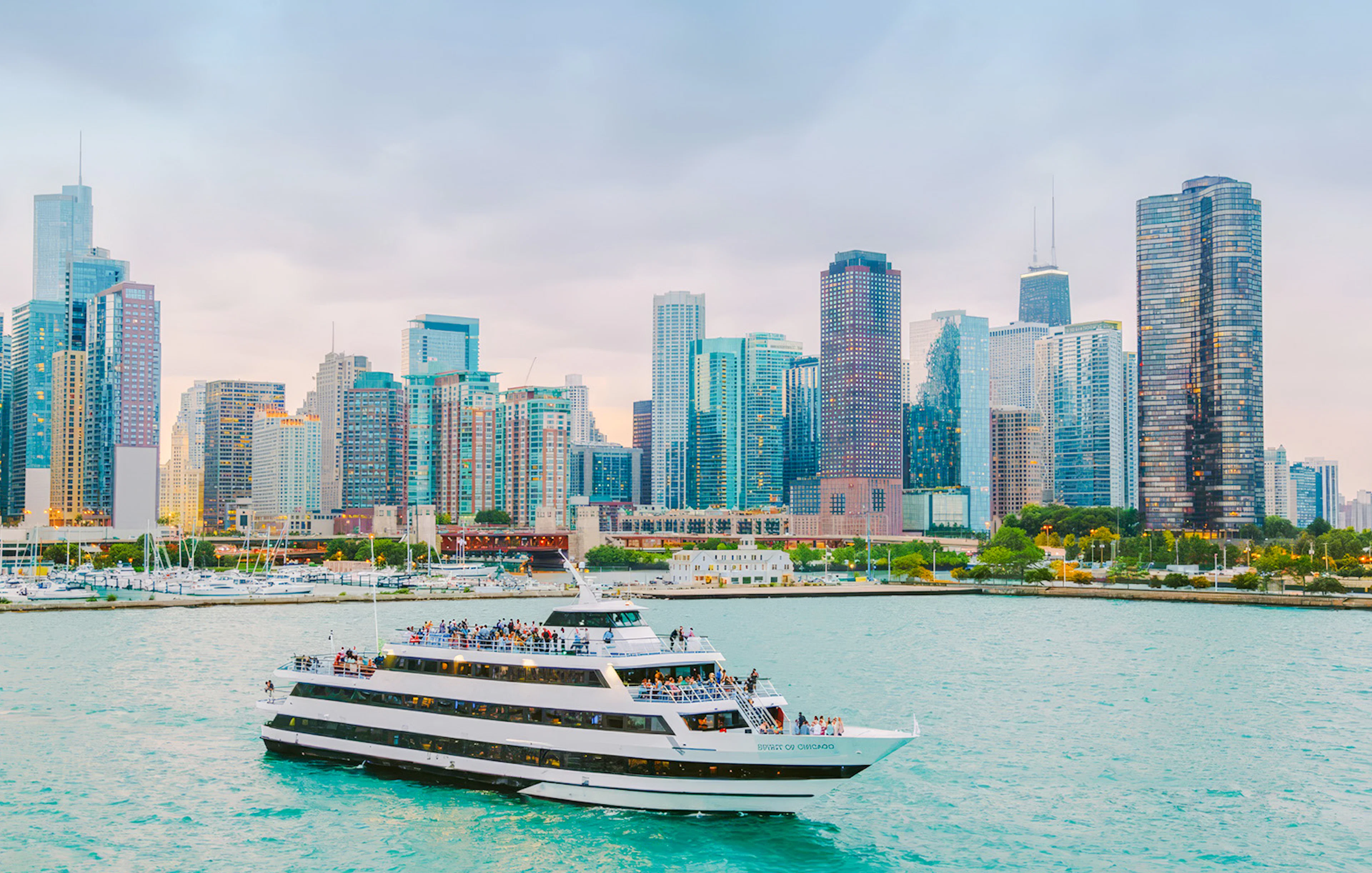 Cruise boat on Chicago River with city skyline in background.