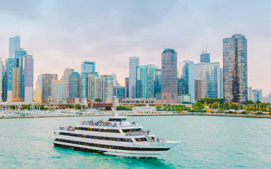 Cruise boat on Chicago River with city skyline in background.