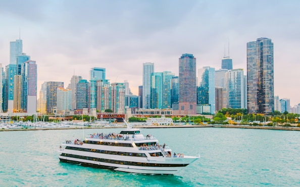 Cruise boat on Chicago River with city skyline in background.