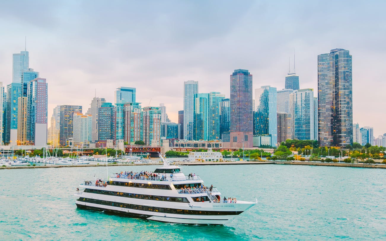Cruise boat on Chicago River with city skyline in background.