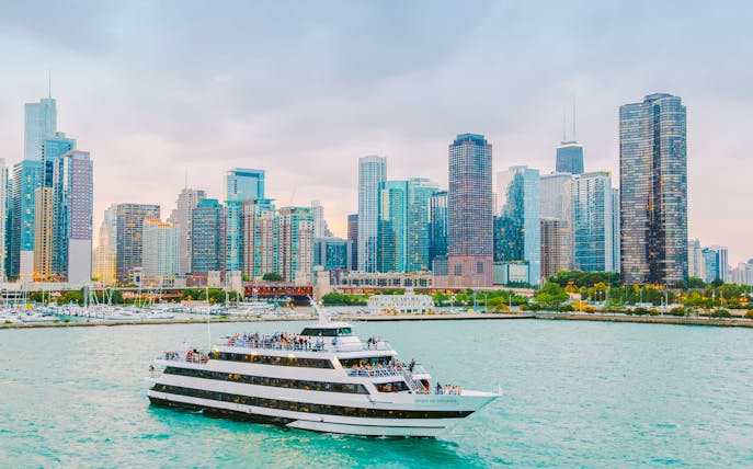 Cruise boat on Chicago River with city skyline in background.