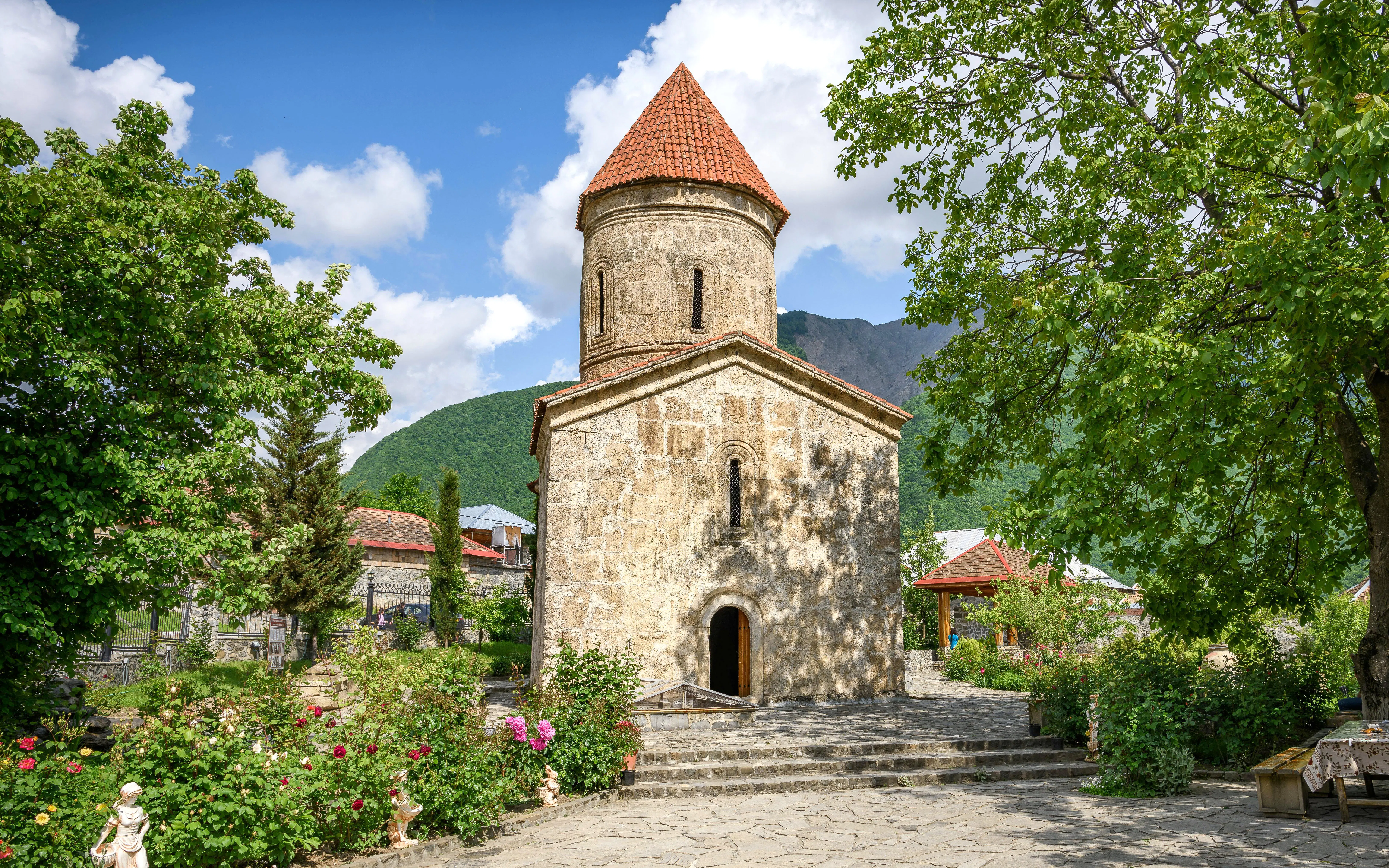 Albanian Church in Kish, Azerbaijan surrounded by greenery and mountains.