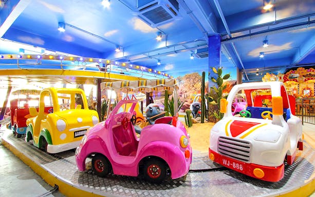Colorful indoor amusement ride with toy cars and Wild West decor.