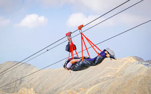 Person ziplining in Jebel Jais mountains, experiencing Jais Flight.