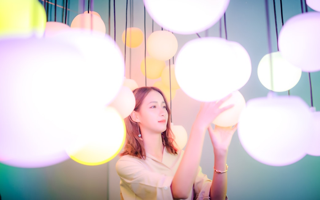 Person interacting with glowing orbs at Space & Time Cube exhibit in Bangkok.