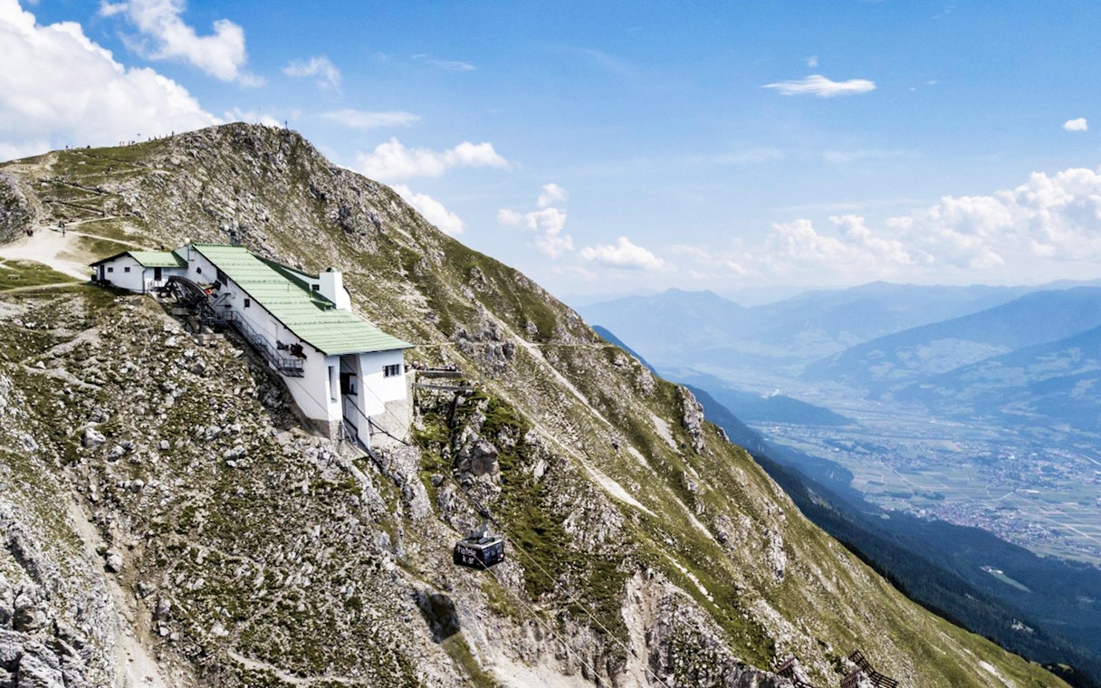 Nordkettenbahn cable car ascending mountain with panoramic view of Innsbruck, Austria.