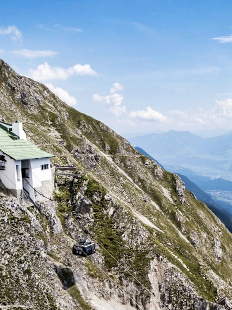 Nordkettenbahn cable car ascending mountain with panoramic view of Innsbruck, Austria.