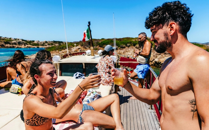 People enjoying drinks on a motorboat tour in La Maddalena Archipelago, Italy.