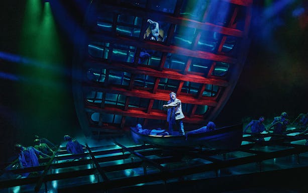 Stage performance of "Swept Away" with actors in a boat under dramatic lighting.