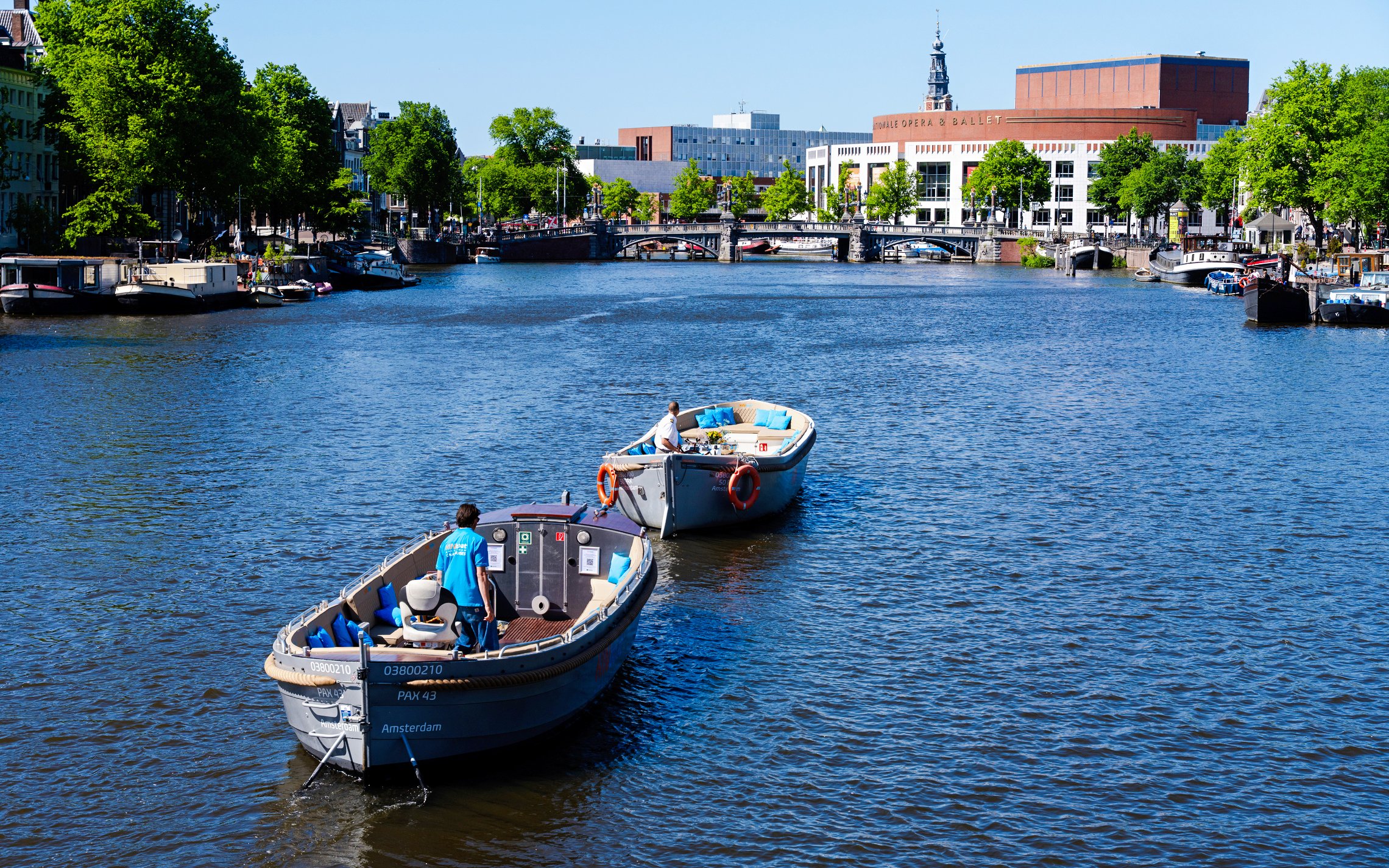 Open boat canal cruise with guests in Amsterdam, passing by the Royal Opera House.