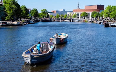 Open boat canal cruise with guests in Amsterdam, passing by the Royal Opera House.