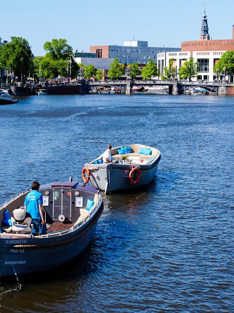Open boat canal cruise with guests in Amsterdam, passing by the Royal Opera House.