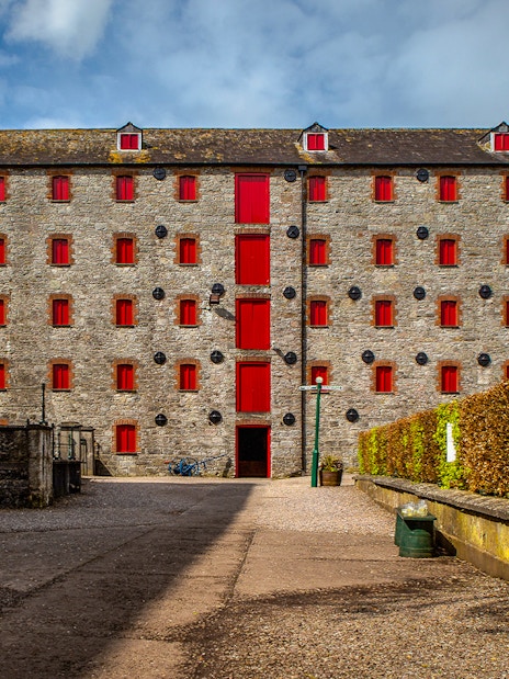 Stone building with red windows at Midleton Distillery, Ireland, for the Behind the Scenes Tour & Tasting.