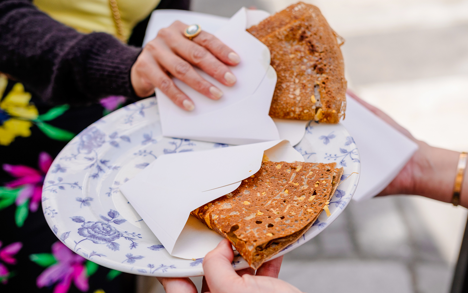 Hands holding a plate with folded crepes during Emily in Paris Food Tour.