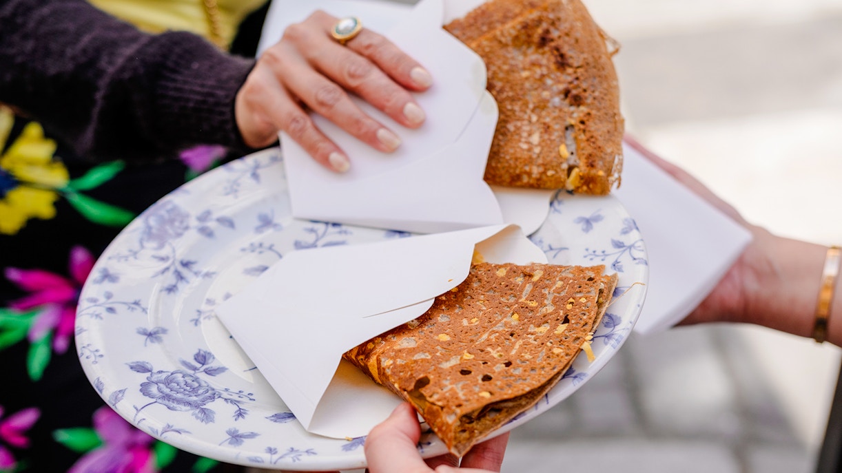 Hands holding a plate with folded crepes during Emily in Paris Food Tour.