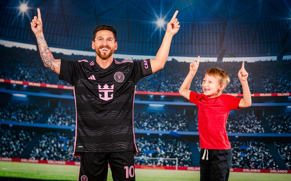 Wax figure of a soccer player with a child at Madame Tussauds Orlando stadium exhibit.