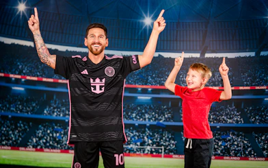 Wax figure of a soccer player with a child at Madame Tussauds Orlando stadium exhibit.
