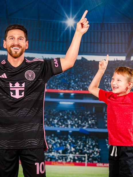 Wax figure of a soccer player with a child at Madame Tussauds Orlando stadium exhibit.