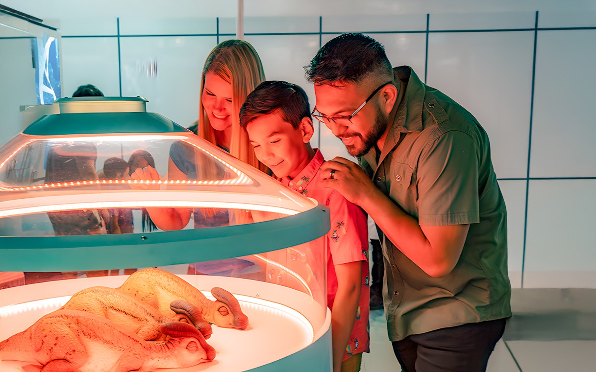 Family observing dinosaur eggs at Jurassic World Experience, London.