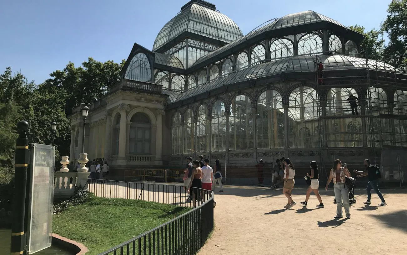 Crystal Palace in Retiro Park, Madrid, with visitors exploring the area.