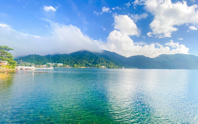 Lake Chūzenji in Nikko with surrounding mountains and clear blue water.