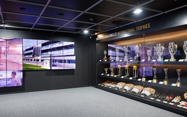 Bernabéu tour display of international trophies and video screens.