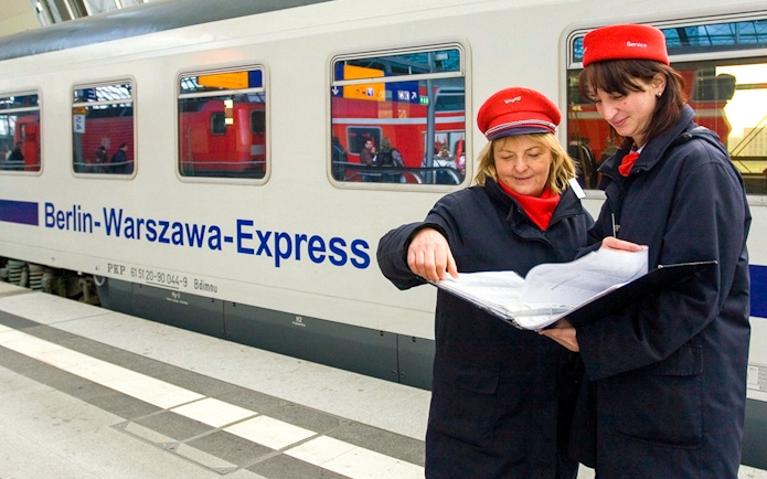 Berlin-Warsaw Express staff discussing schedules on the platform.