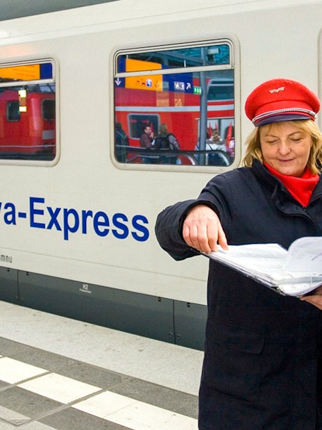 Berlin-Warsaw Express staff discussing schedules on the platform.