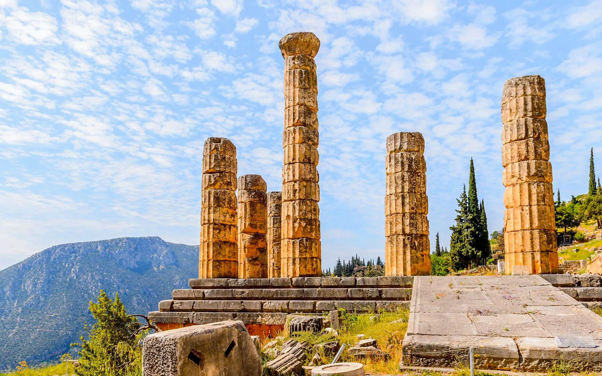 Temple of Apollo ruins at Delphi Archaeological Site with mountain backdrop, near Athens.