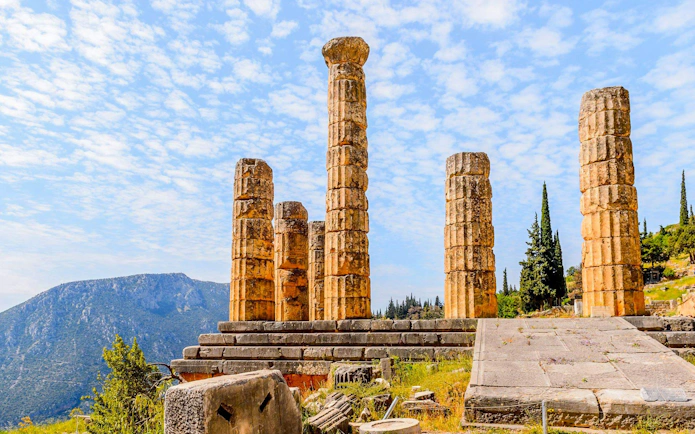 Temple of Apollo ruins at Delphi Archaeological Site with mountain backdrop, near Athens.