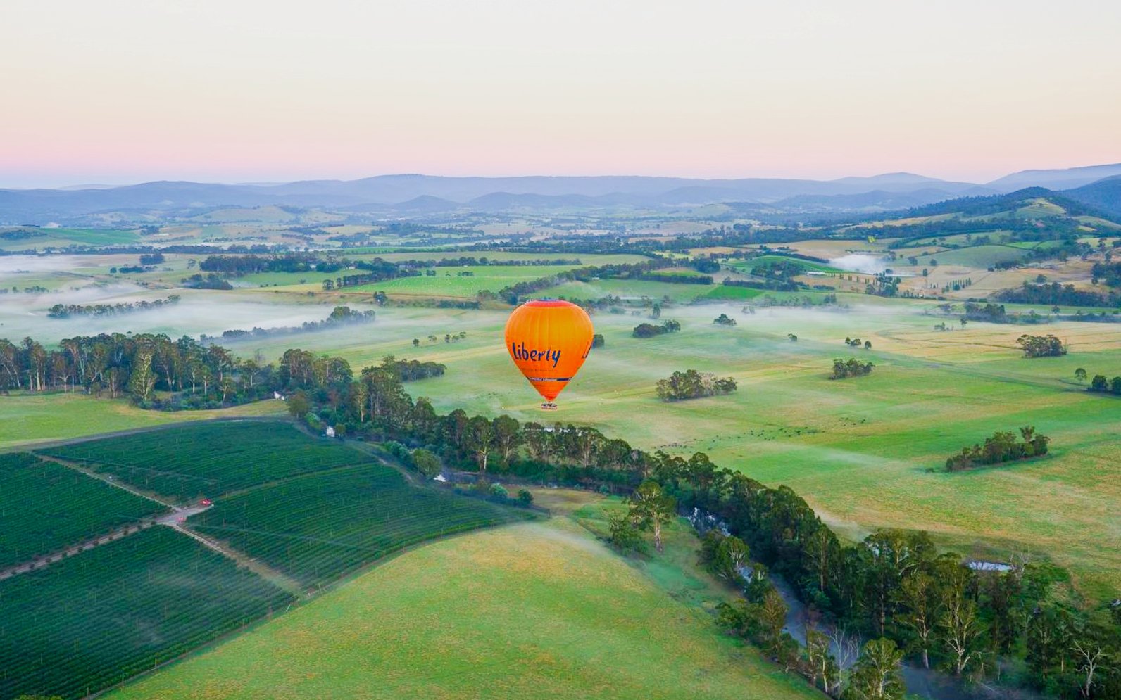 Hot air balloon over Yarra Valley landscape at sunset.