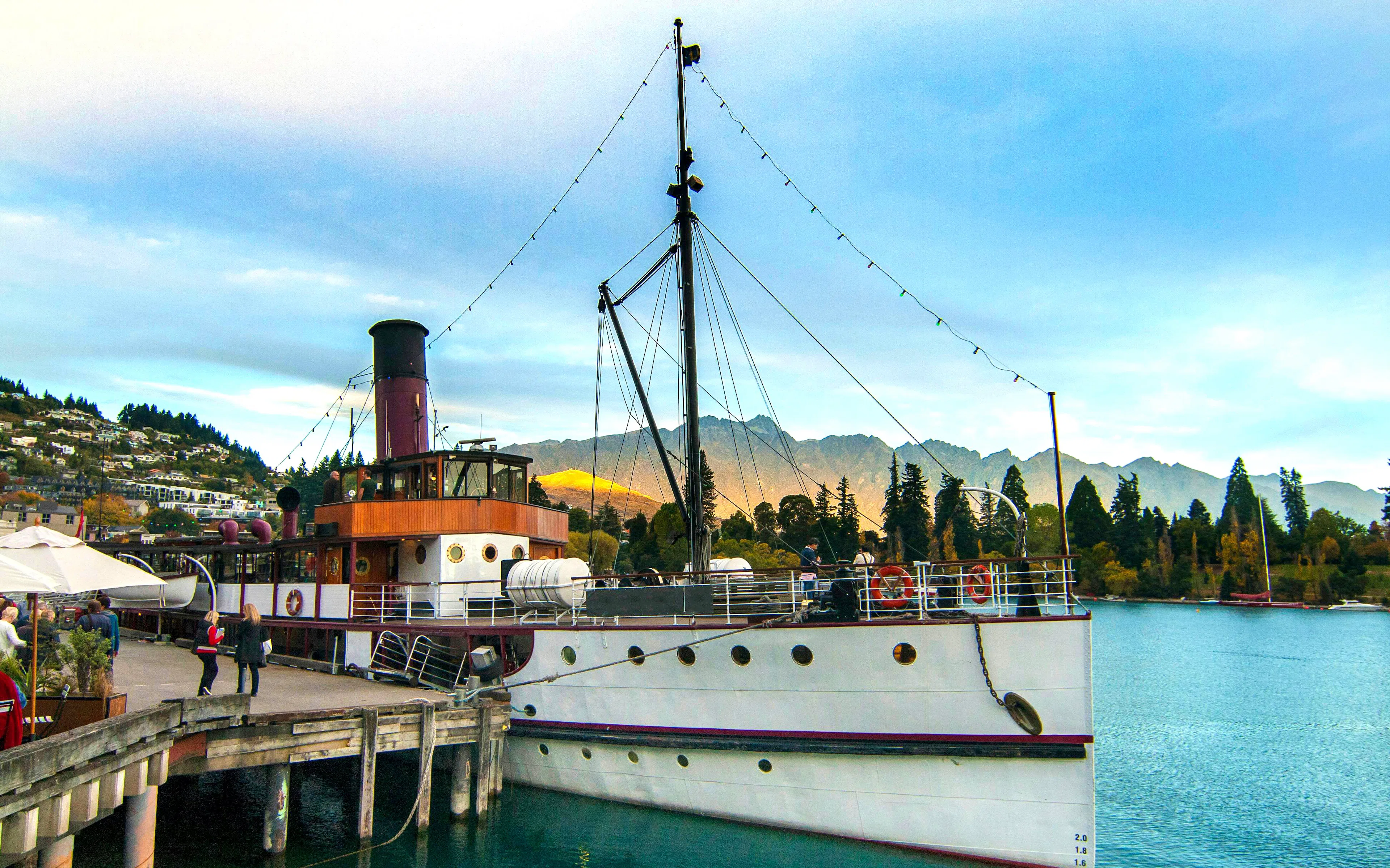 TSS Earnslaw docked at Queenstown Wharf with mountains in the background.