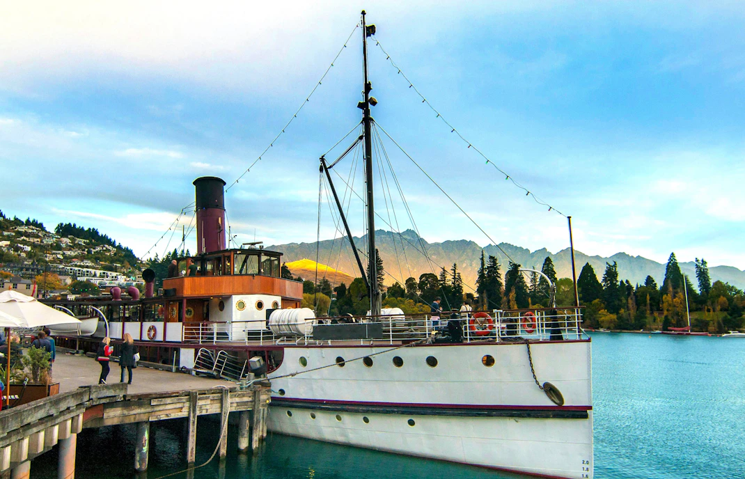 TSS Earnslaw docked at Queenstown Wharf with mountains in the background.