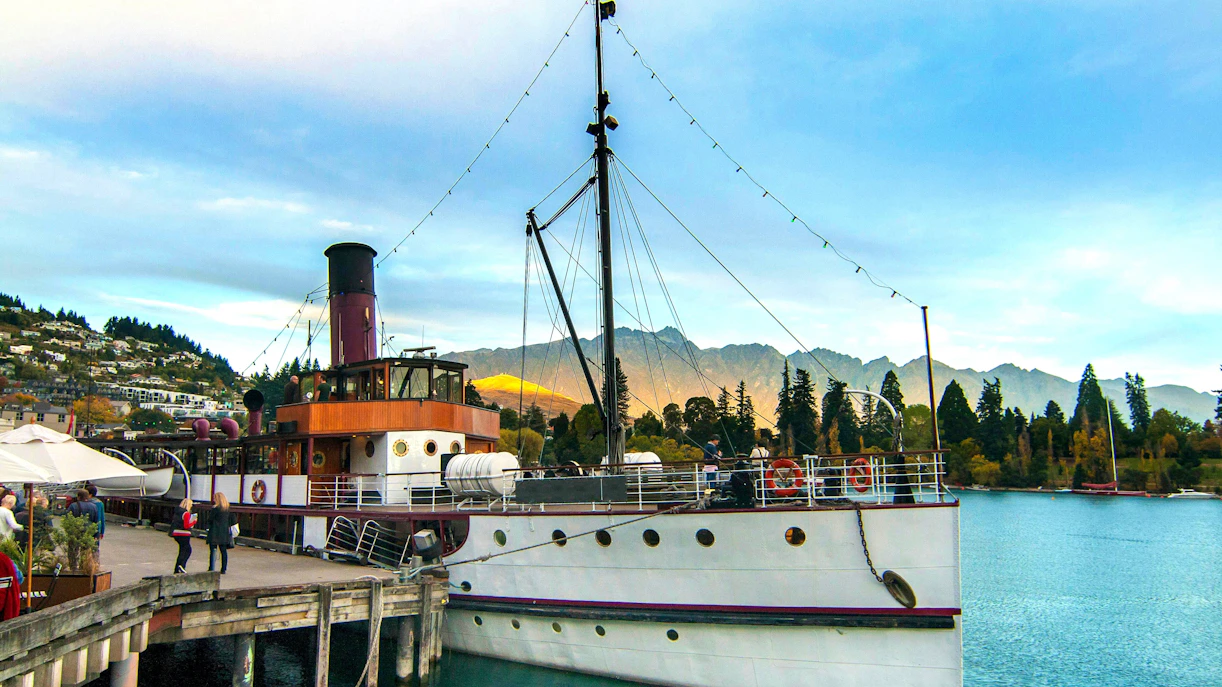 TSS Earnslaw docked at Queenstown Wharf with mountains in the background.