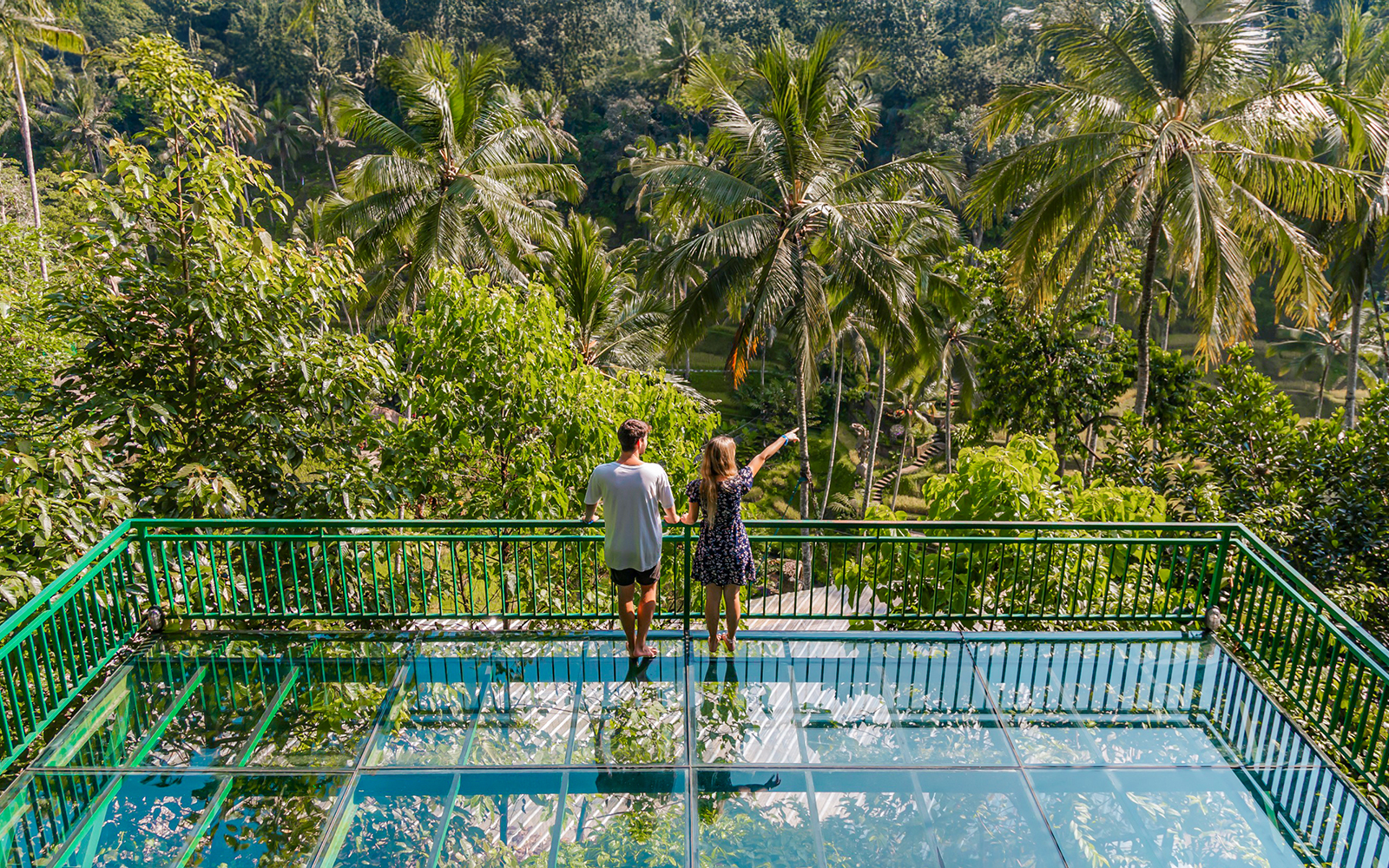 Couple on glass terrace overlooking lush greenery at Alas Harum Bali.