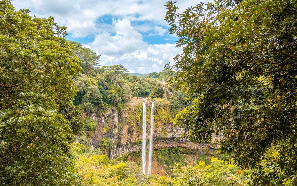 Chamarel waterfall in Mauritius surrounded by lush greenery from a viewpoint.