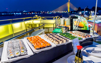 Sushi buffet on Alangka Dinner Cruise at IconSiam Pier No.4 with city lights in background.