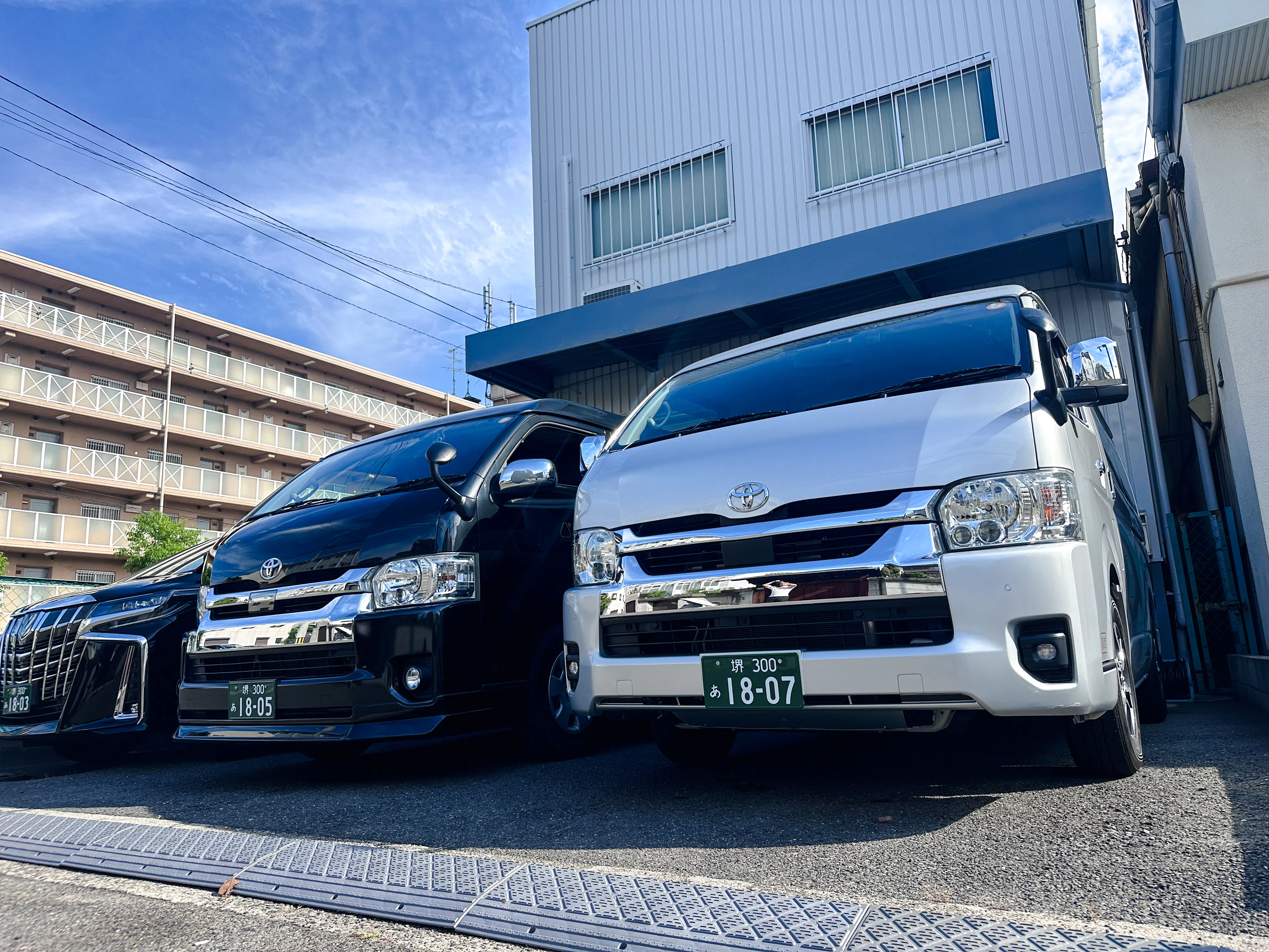 Private transfer vans parked outside a building in Osaka for Kansai Airport service.