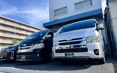 Private transfer vans parked outside a building in Osaka for Kansai Airport service.