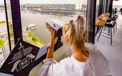 Person using a viewer at ADAM Lookout indoor panorama deck, overlooking Amsterdam.