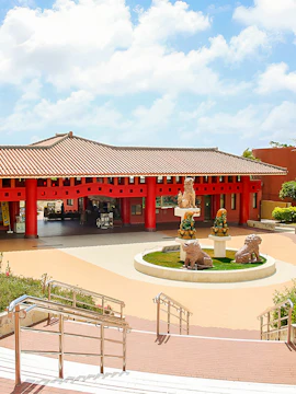Okinawa World entrance with traditional red pillars and lion statues.