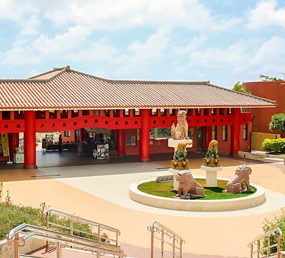 Okinawa World entrance with traditional red pillars and lion statues.