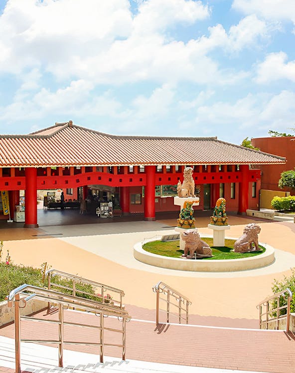 Okinawa World entrance with traditional red pillars and lion statues.
