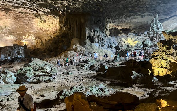 Visitors exploring Bo Hon Cave, Ha Long Bay, observing stalactites and unique rock formations.