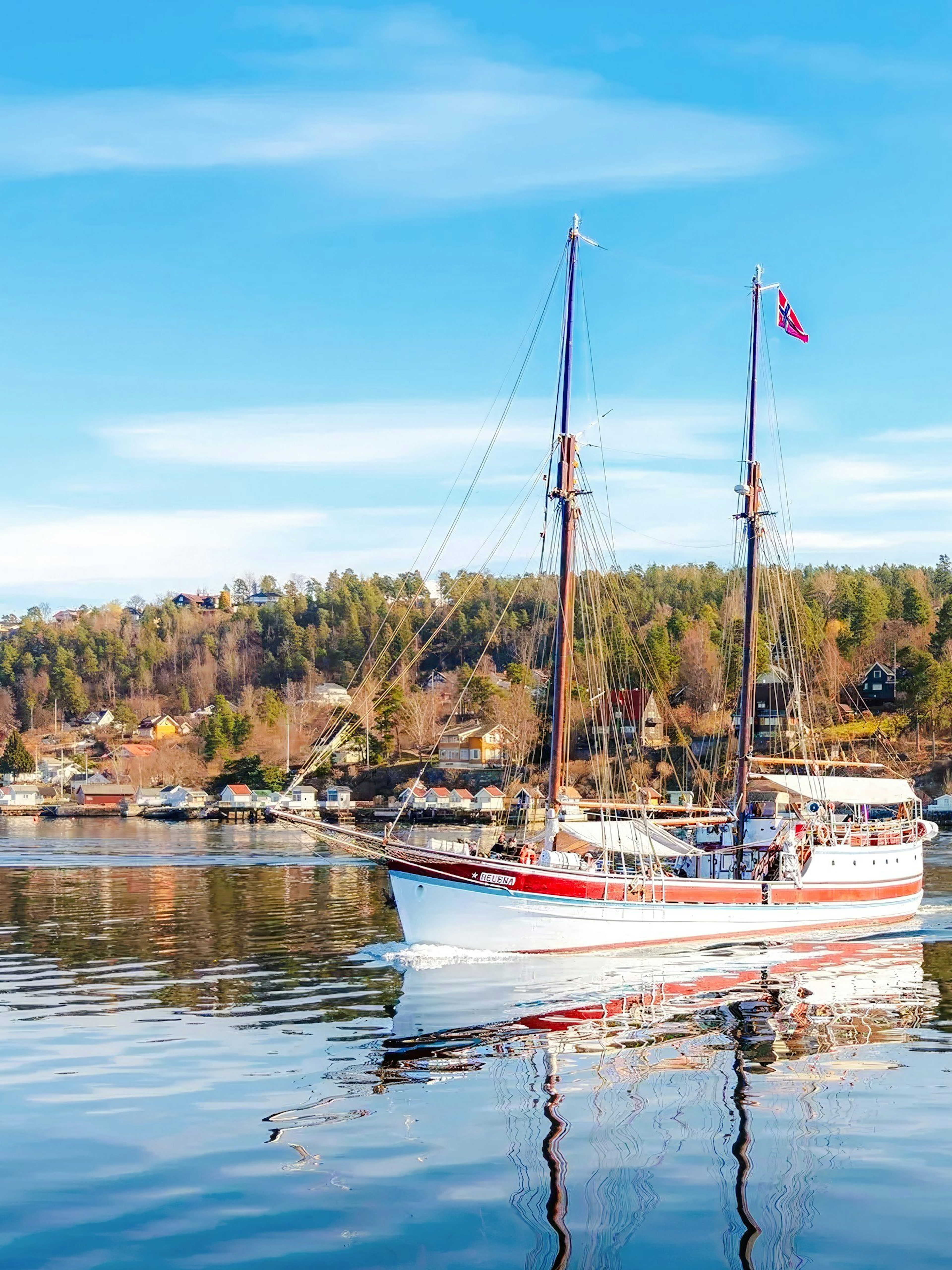 Sailing ship on Oslo fjord sightseeing cruise with coastal landscape.