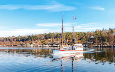 Sailing ship on Oslo fjord sightseeing cruise with coastal landscape.