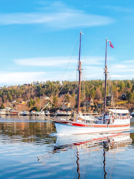 Sailing ship on Oslo fjord sightseeing cruise with coastal landscape.