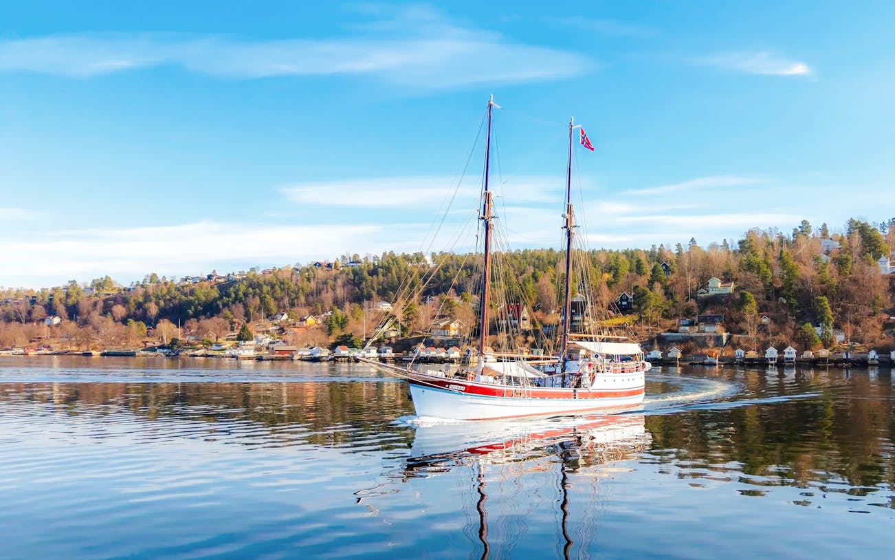 Sailing ship on Oslo fjord sightseeing cruise with coastal landscape.