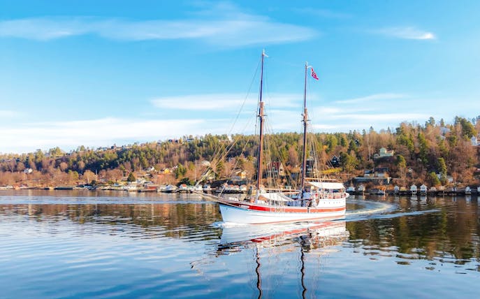 Sailing ship on Oslo fjord sightseeing cruise with coastal landscape.
